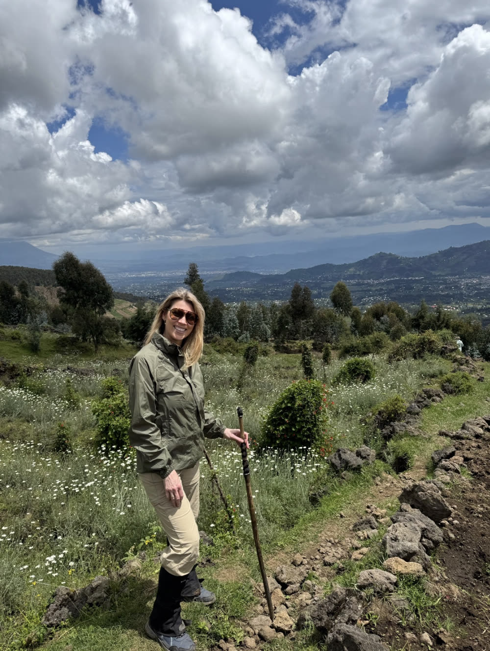 Kate Whelan walking in the green hills of Rwanda with a walking stick.